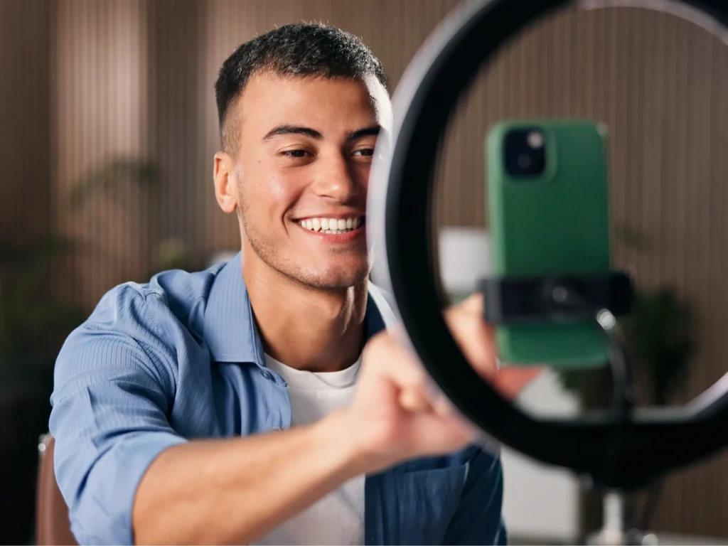 Hombre joven grabando contenido con ring light y smartphone para OnlyFans