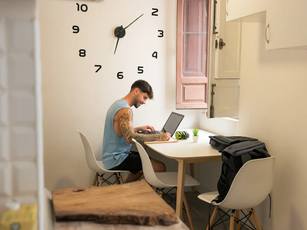 Hombre tatuado trabajando en laptop gestionando su perfil de OnlyFans